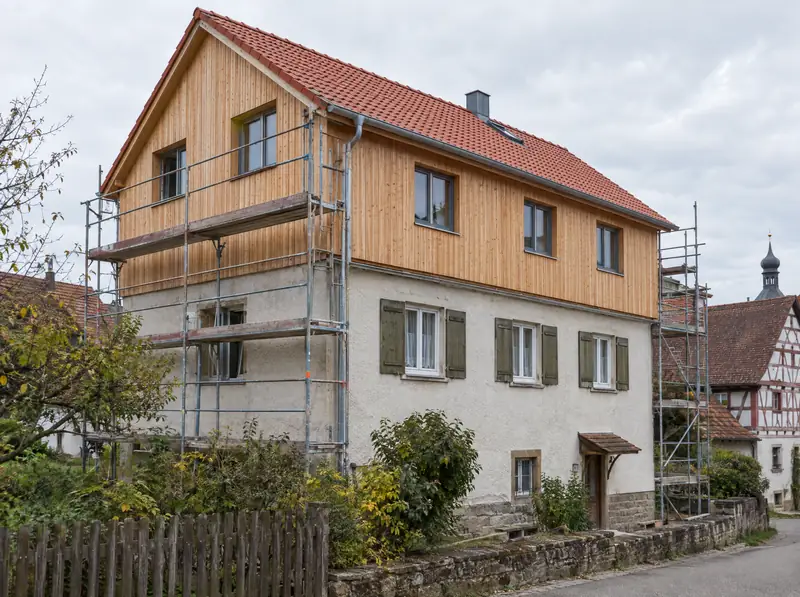 Wohnhaus mit neuem Obergeschoss aus Holz und Gerüst an der Seite